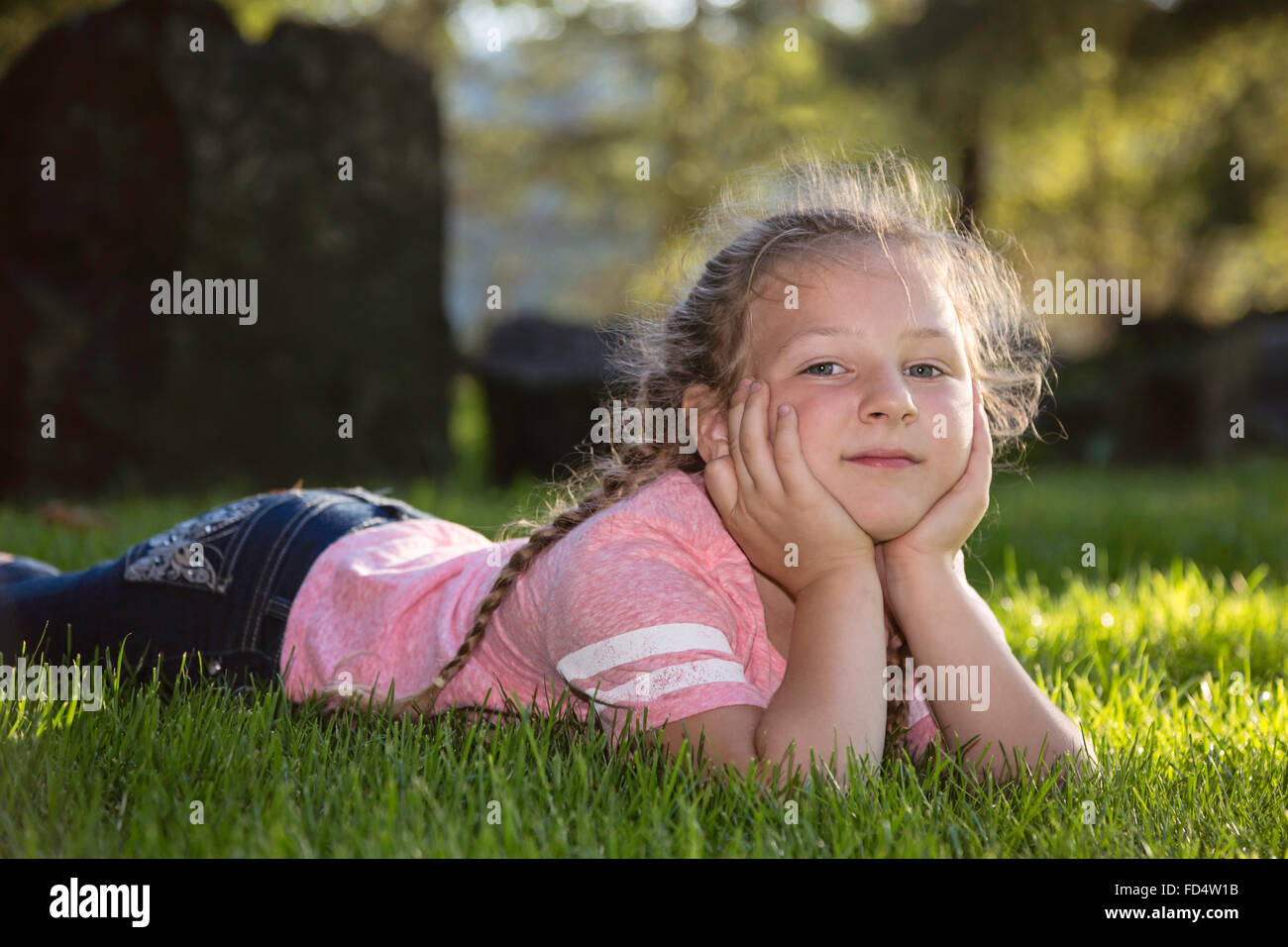 Happy young girl laying in the grass at the park Stock Photo - Alamy