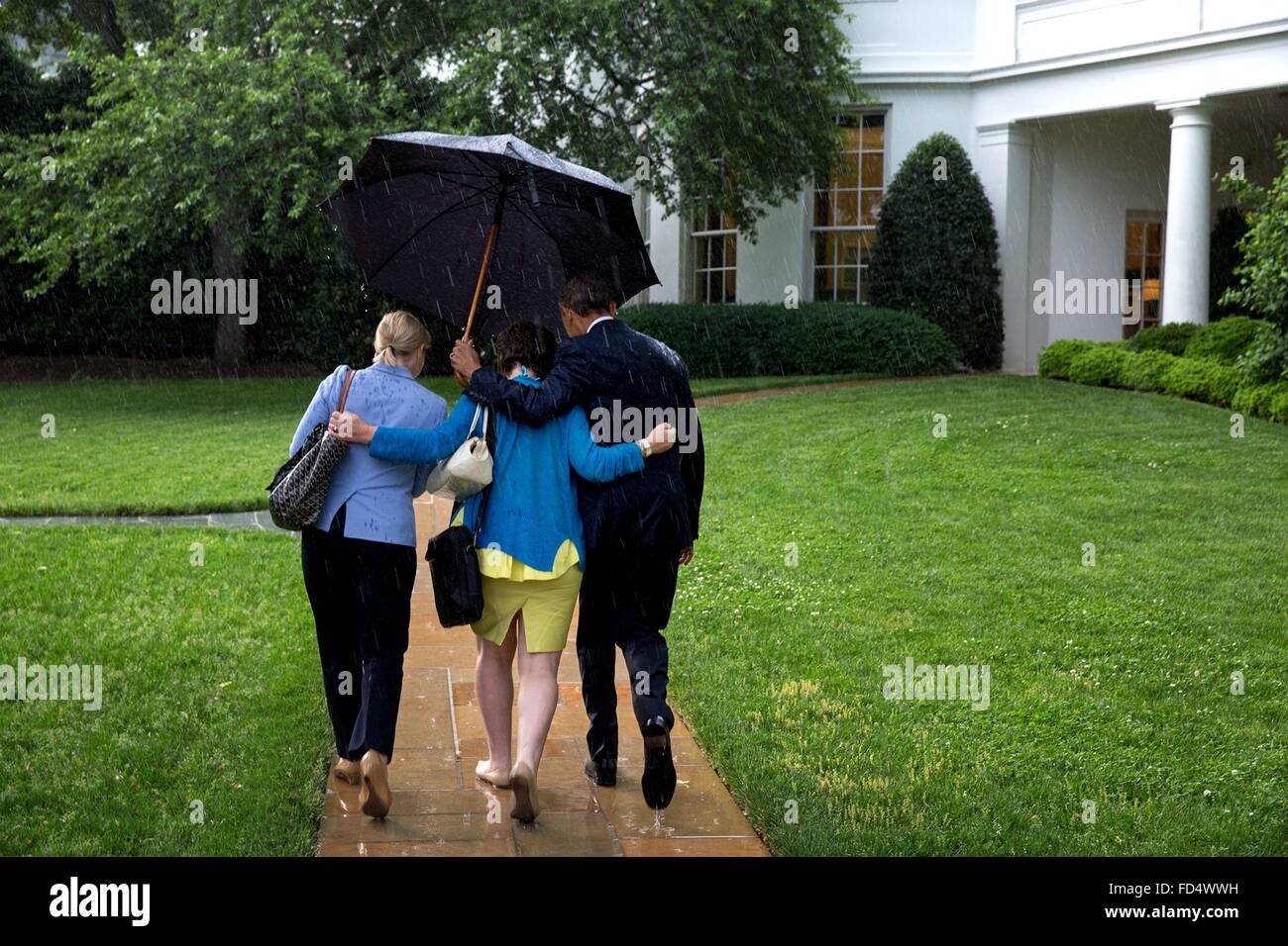 U.S. President Barack Obama holds an umbrella for aides Valerie Jarrett and Anita Decker Breckenridge after returning on Marine One to the West Wing of the White House May 18, 2015 in Washington, DC. Stock Photo