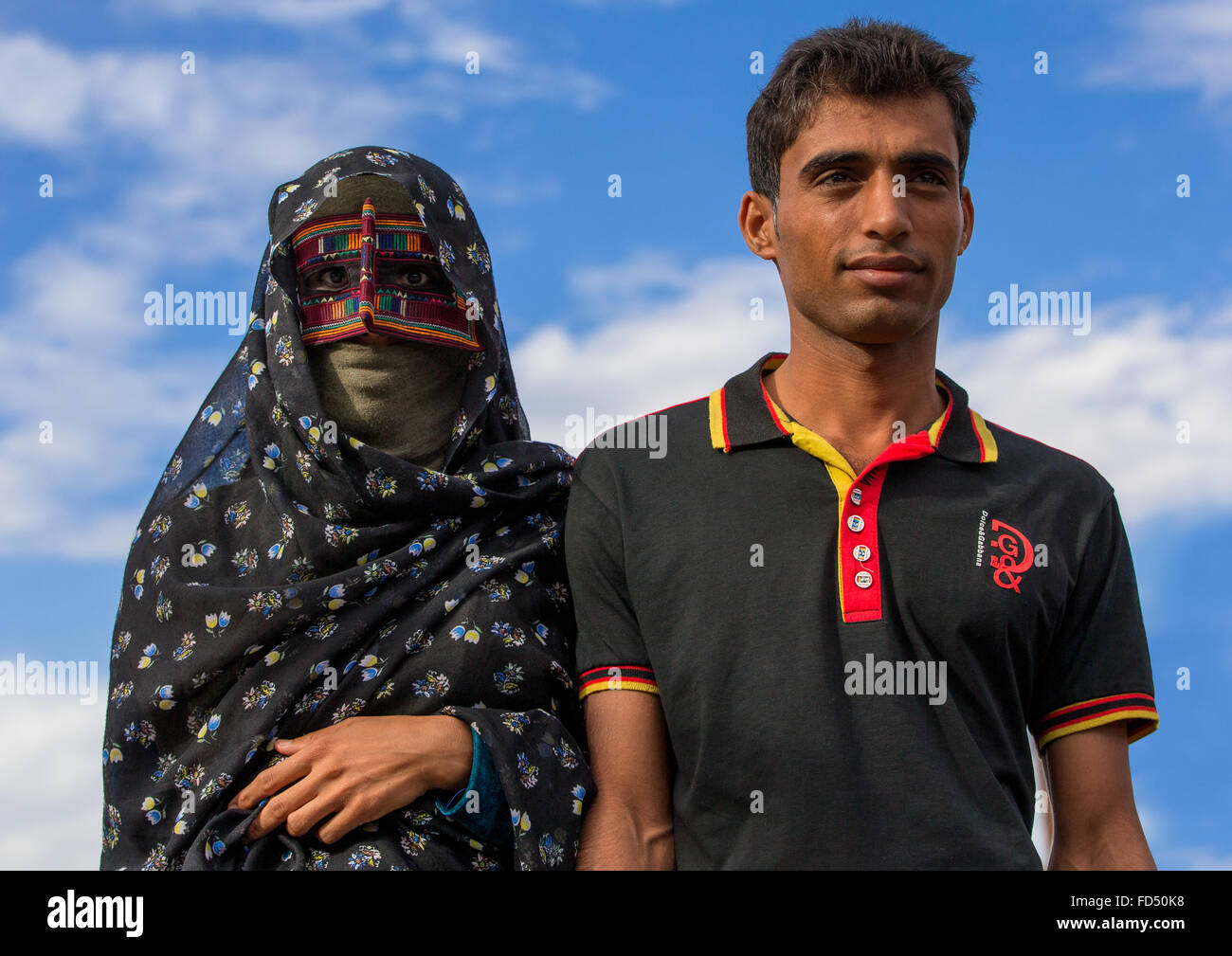 a bandari woman with her husband wearing a traditional mask called the burqa at panjshambe bazar, Hormozgan, Minab, Iran Stock Photo