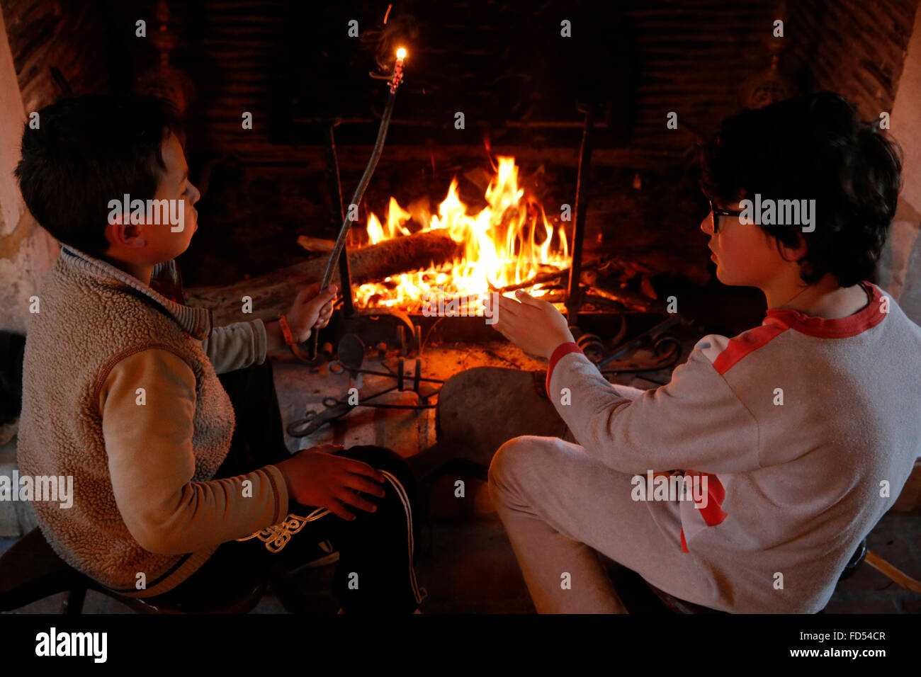 8-year-old boys sitting by a fireplace. Stock Photo