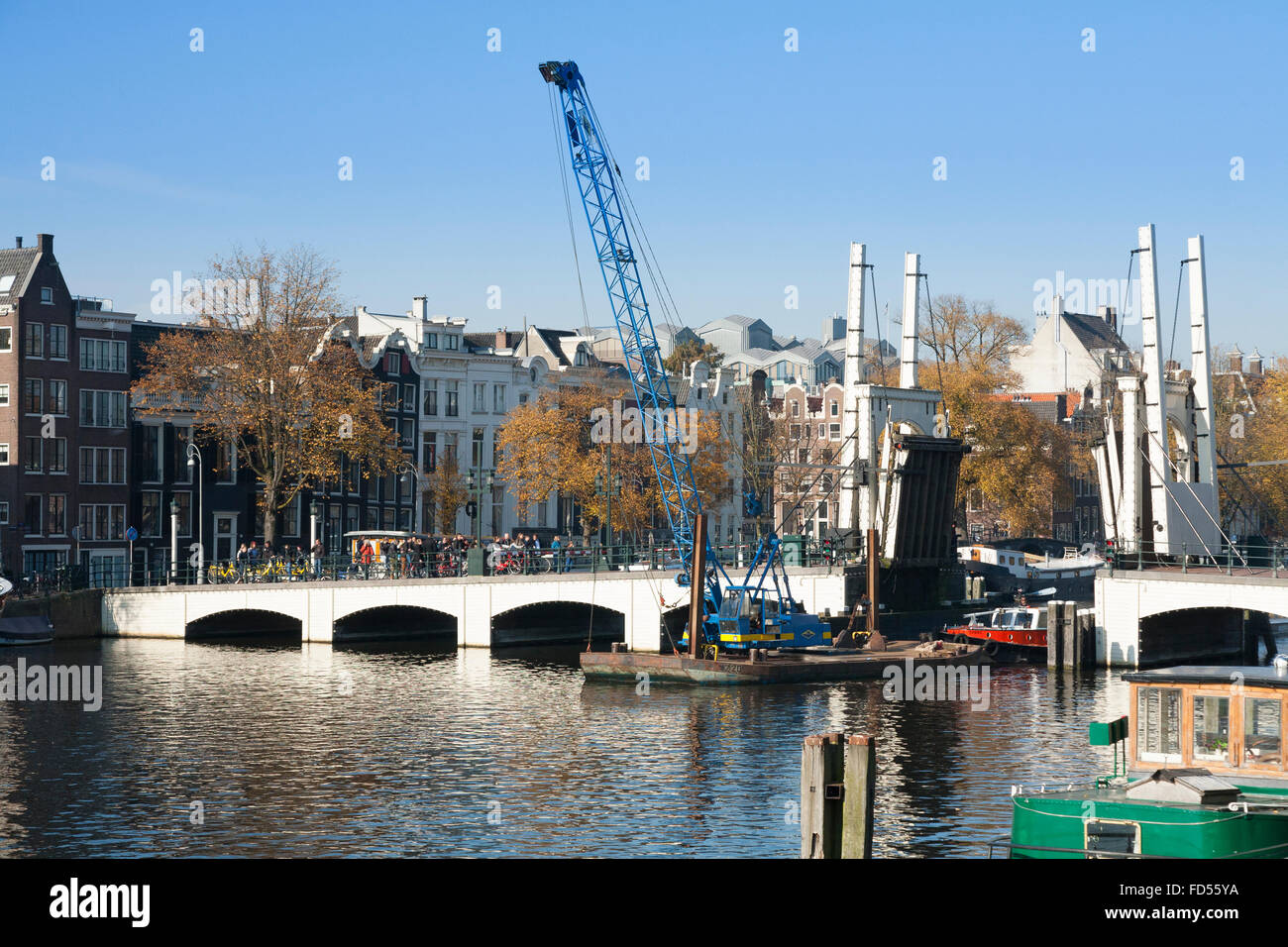Boat / barge passes under the Magere Brug ('Skinny Bridge') in Dutch capital Amsterdam, The Netherlands, Holland. Stock Photo