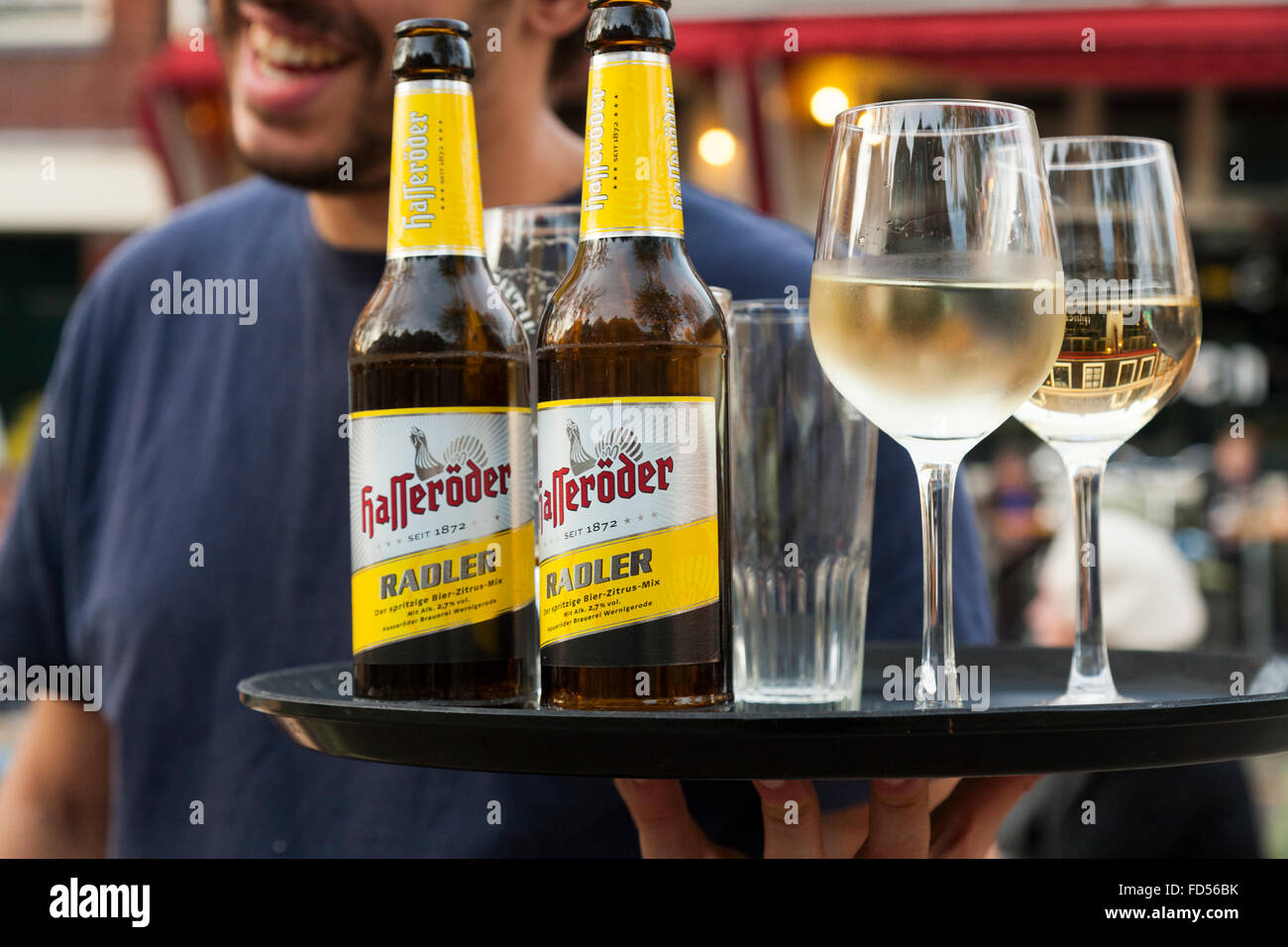 Barman with a tray of drinks including Hasseröder beer and glass / glasses of white wine. Amsterdam, Holland, The Netherlands. Stock Photo