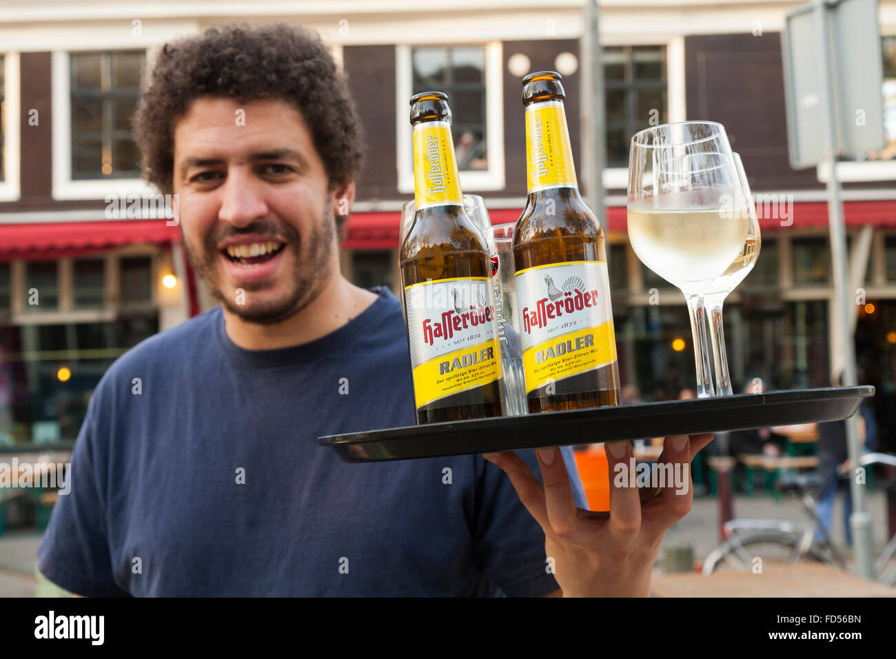 Barman with a tray of drinks including Hasseröder beer and glass / glasses of white wine