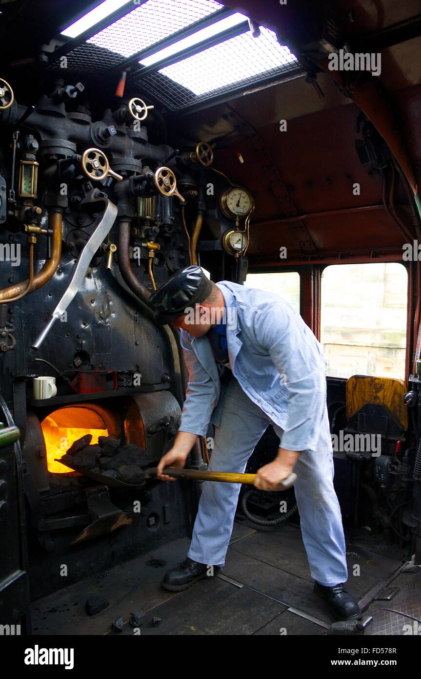Stoker stoking the fire box of steam train LMS Princess Coronation Class 46233 Duchess of Sutherland. Stock Photo