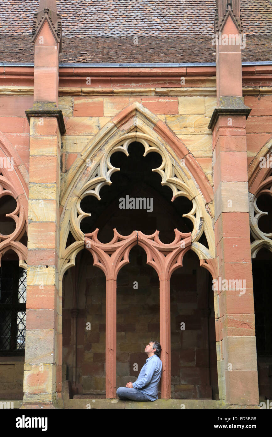 Pilgrim praying in a gothic cloister.  St. Peter and St. Paul's Church. Wissembourg. Stock Photo