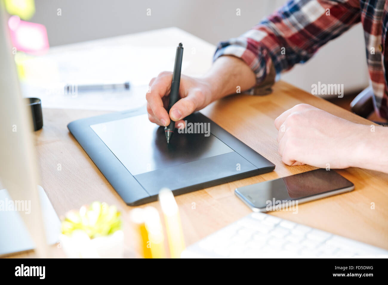 Closeup of black pen tablet with stylus used by male designer hand on