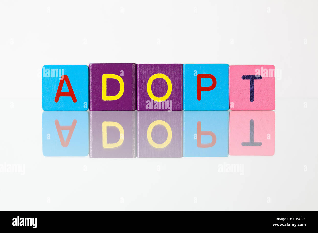 Adopt - an inscription from children's wooden blocks Stock Photo