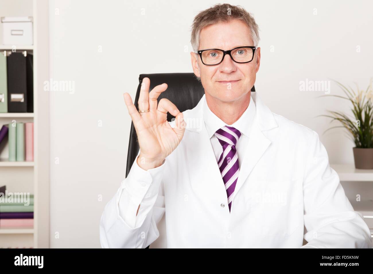 Smiling Doctor Showing Okay Hand Sign Emphasizing Positive Updates Stock Photo