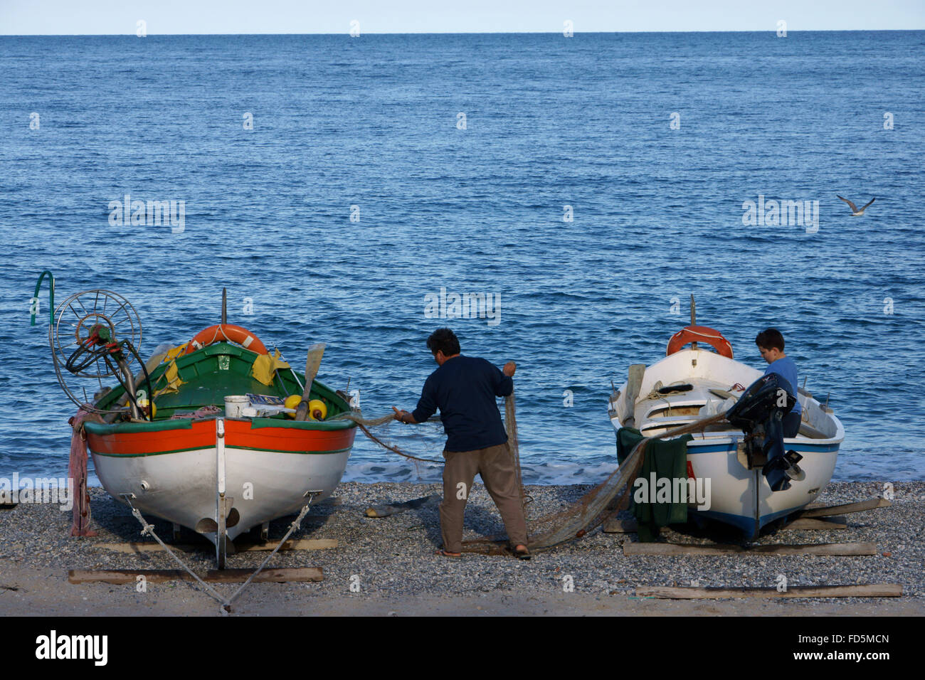 Fisherman sorting nets  on beach at Noli, Riviera di Ponente, Liguria, Italy Stock Photo