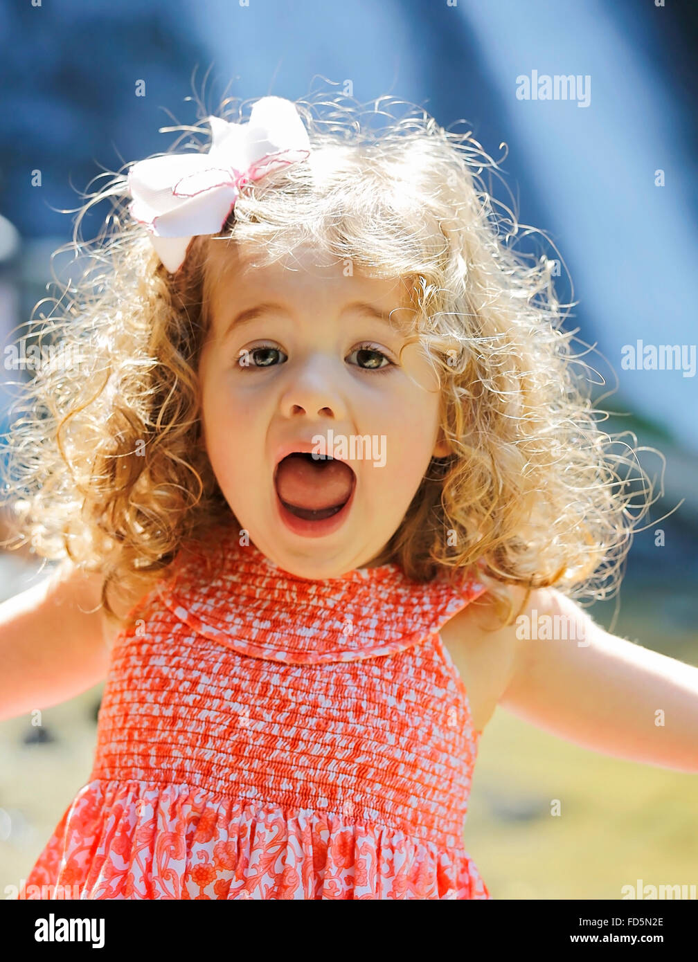 Image of a wild-haired, free-spirited toddler girl screaming with joy. Stock Photo