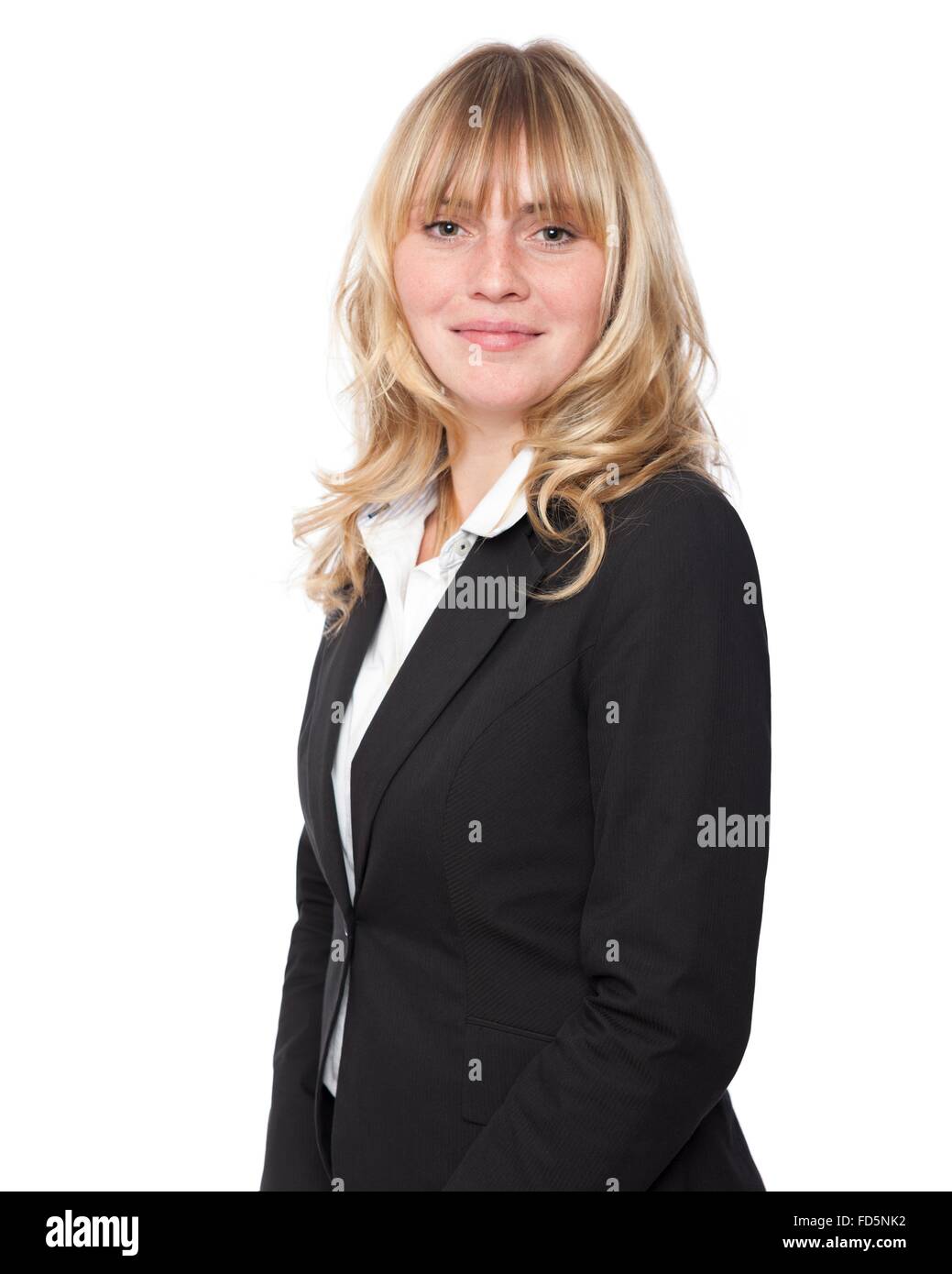 Stylish attractive young businesswoman with long blond hair in a black jacket standing sideways looking at the camera Stock Photo