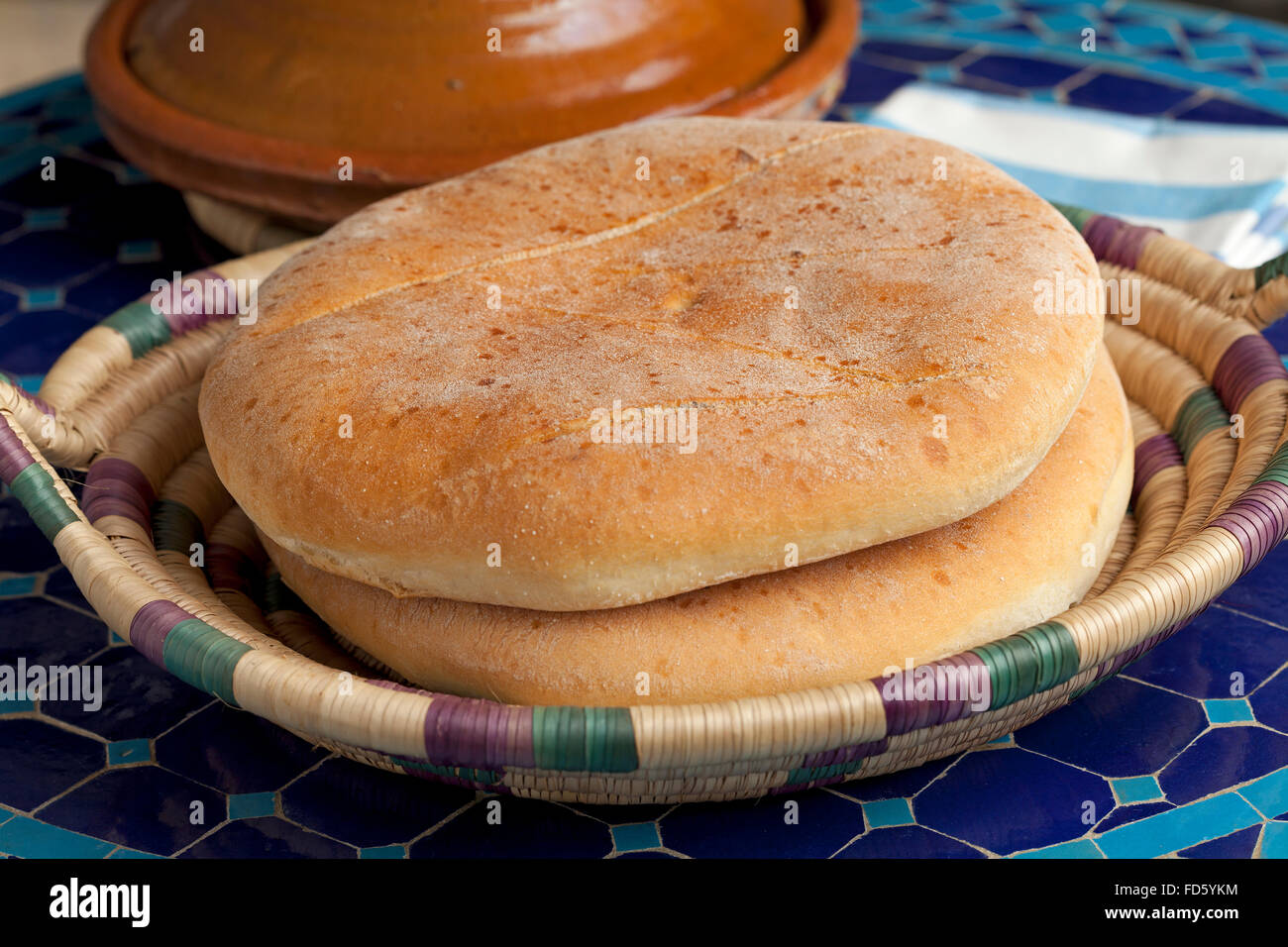 Fresh Moroccan bread in a basket and tagine on the table Stock Photo