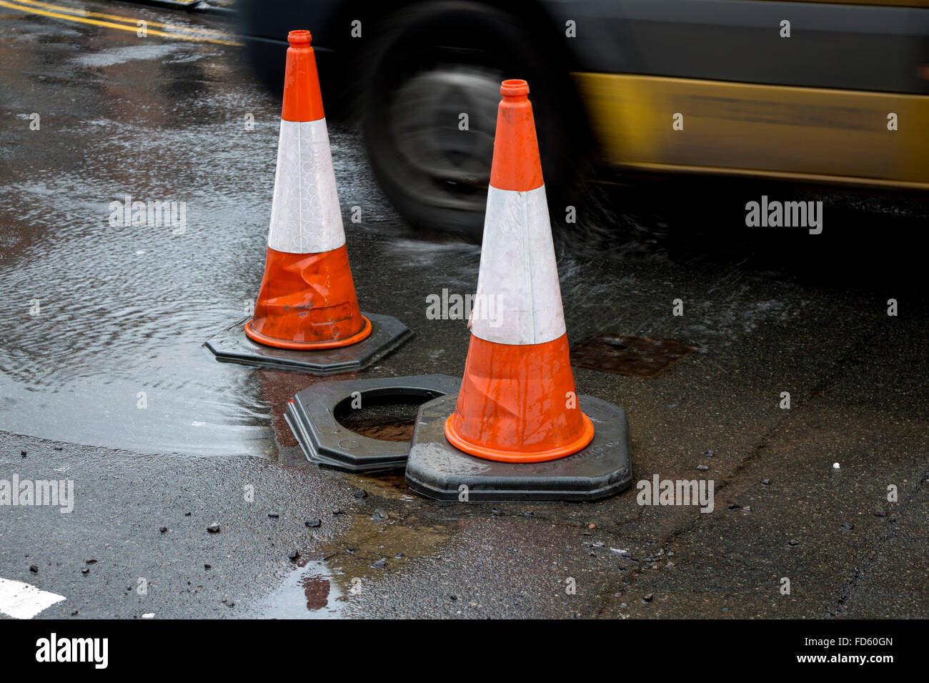 Traffic cones at a water main leak in a road, UK Stock Photo