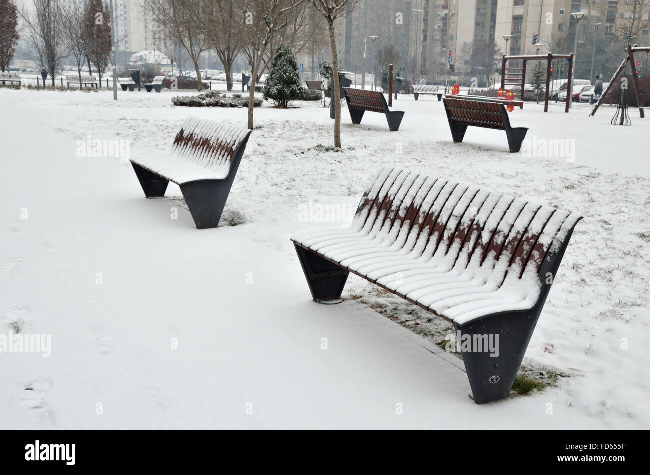 Two benches in city park covered with snow Stock Photo - Alamy