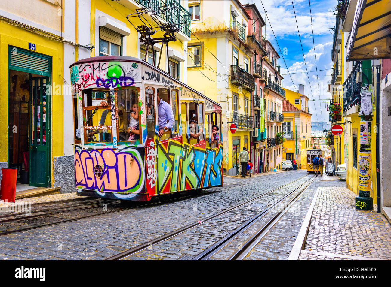 LISBON, PORTUGAL - SEPTEMBER 12, 2014: Pedestrians and trams in Lisbon. The historic trams are a popular attraction. Stock Photo