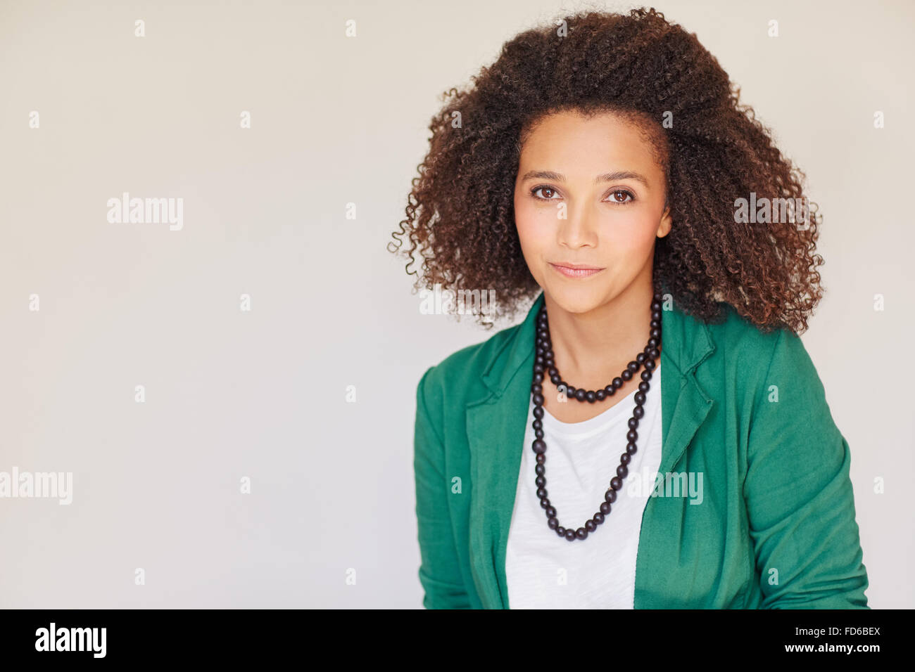 Mixed race businesswon with curly afro in green jacket Stock Photo