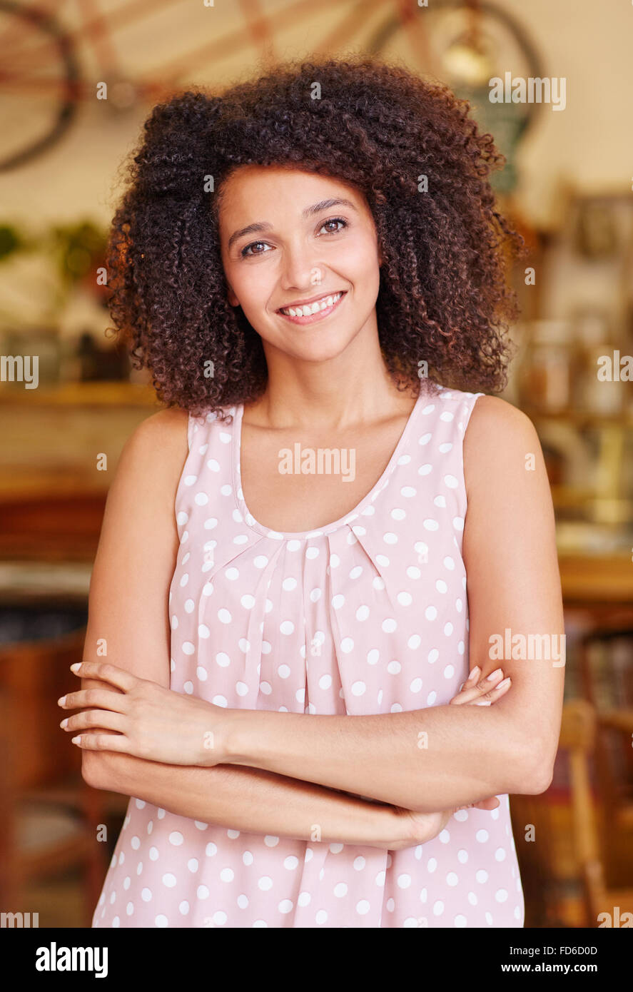 Young woman with her arms crossed smiling in a cafe Stock Photo