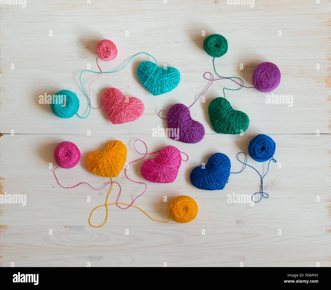 Multicolored Hearts with a balls of thread on white wooden background ...