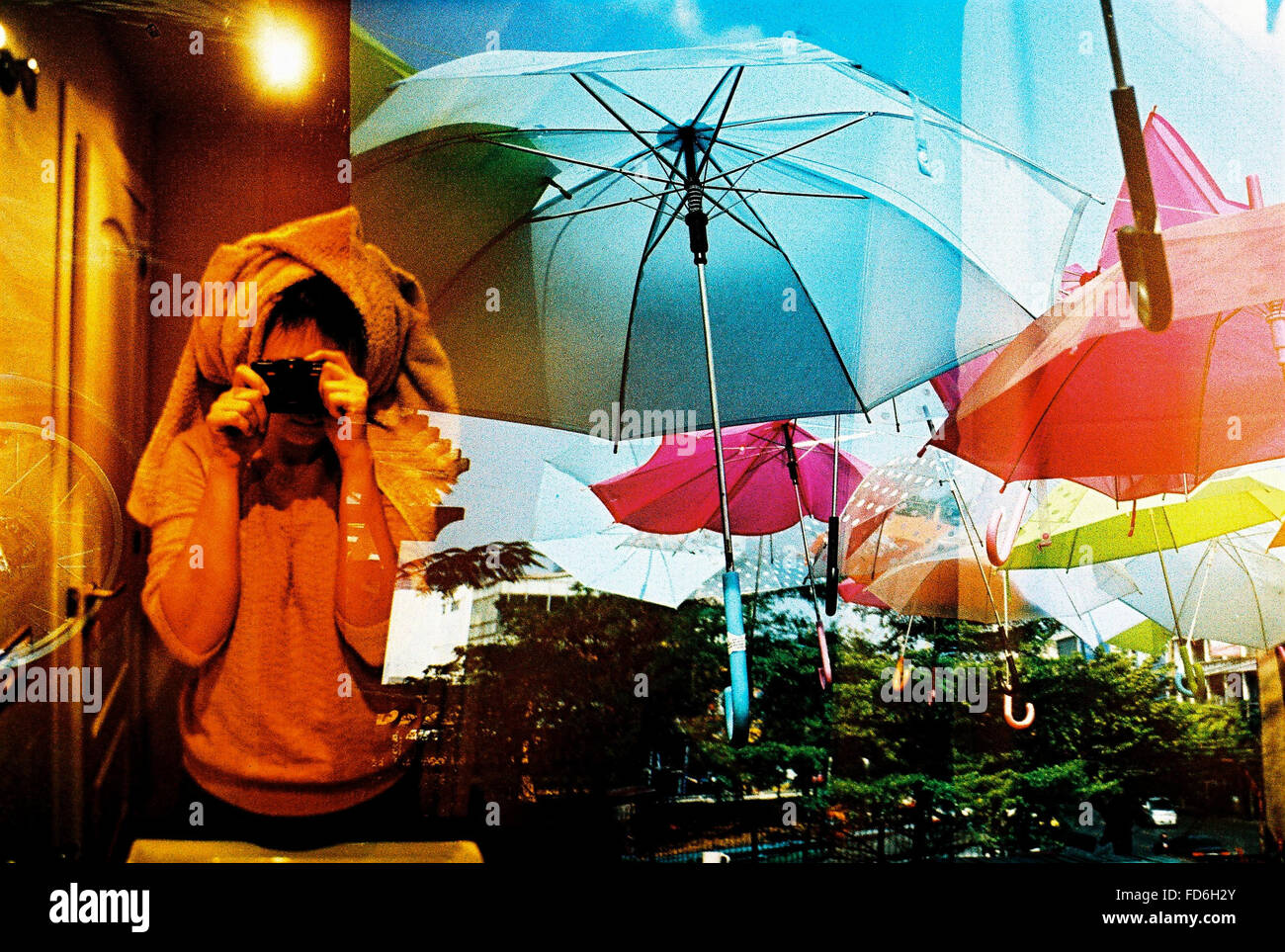 Woman Photographing With Reflection Of Umbrellas On Window Stock Photo