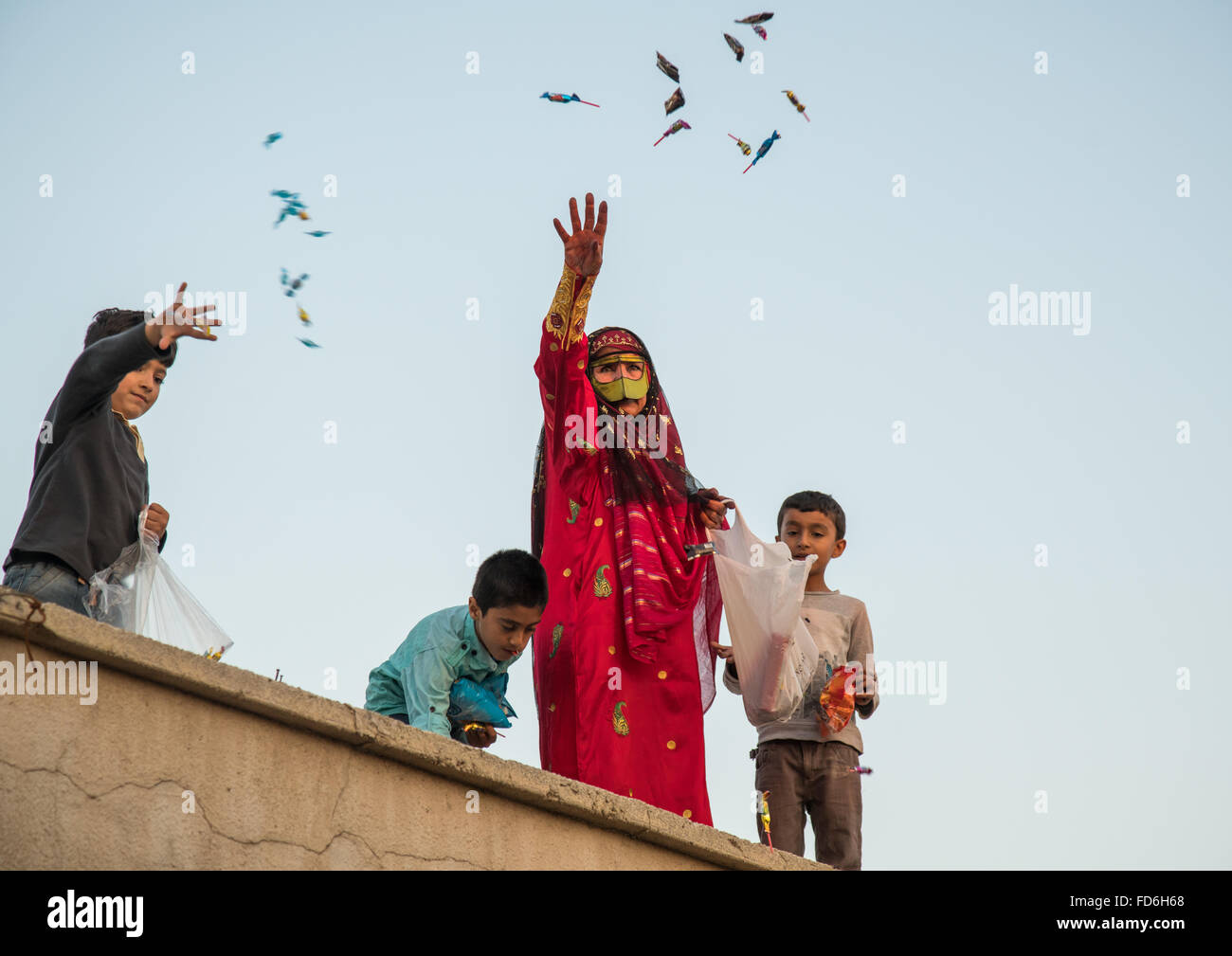 women with face masks throwing sweets to kids during a wedding, Hormozgan, Kushkenar, Iran Stock Photo