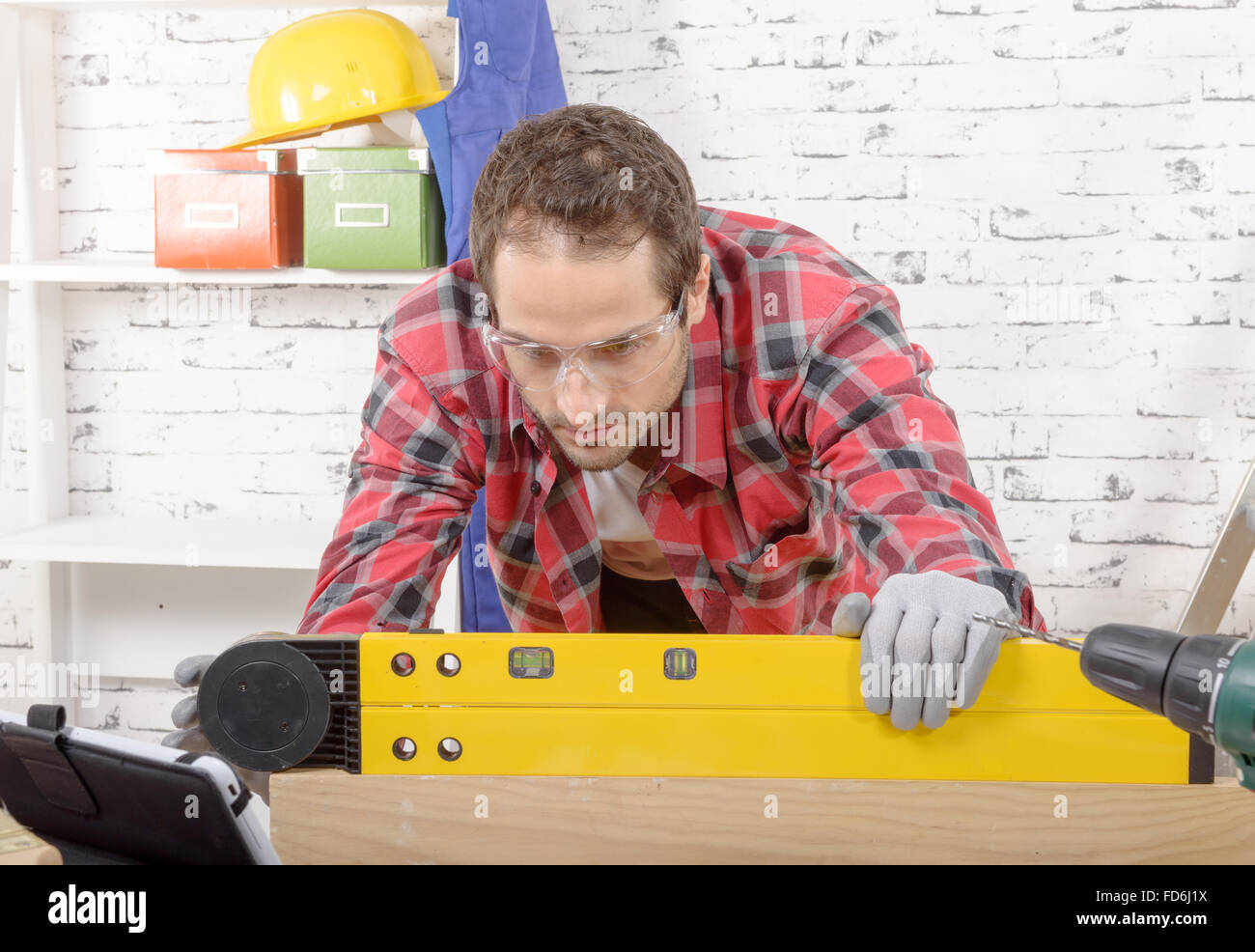a young man viewing a spirit level, to read the position of the bubble ...