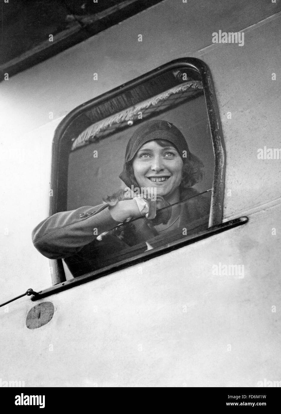Young woman looking past an open airplane window, 1929 Stock Photo