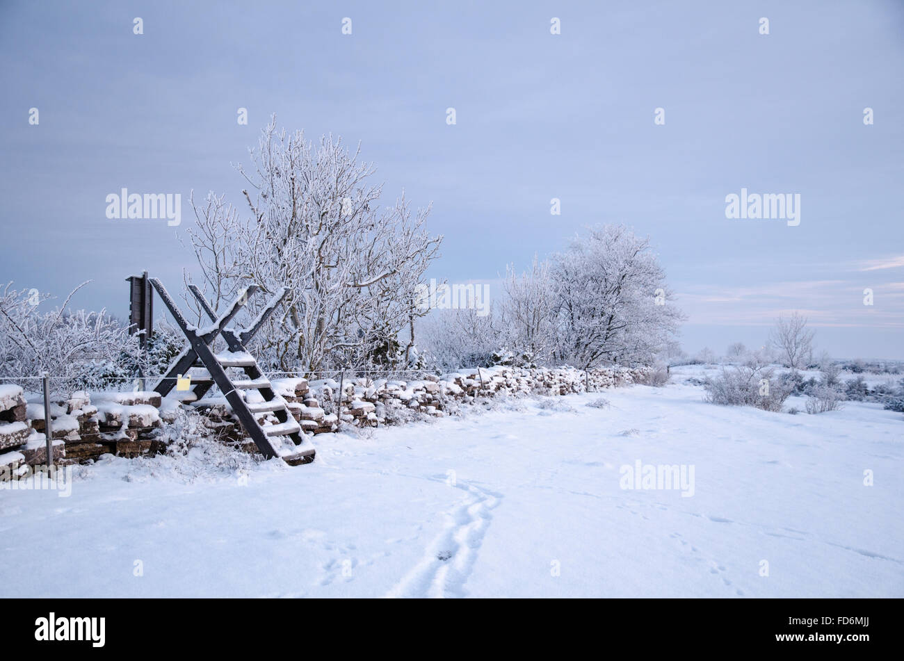 Winter landscape with a stile at a snow covered stone wall Stock Photo
