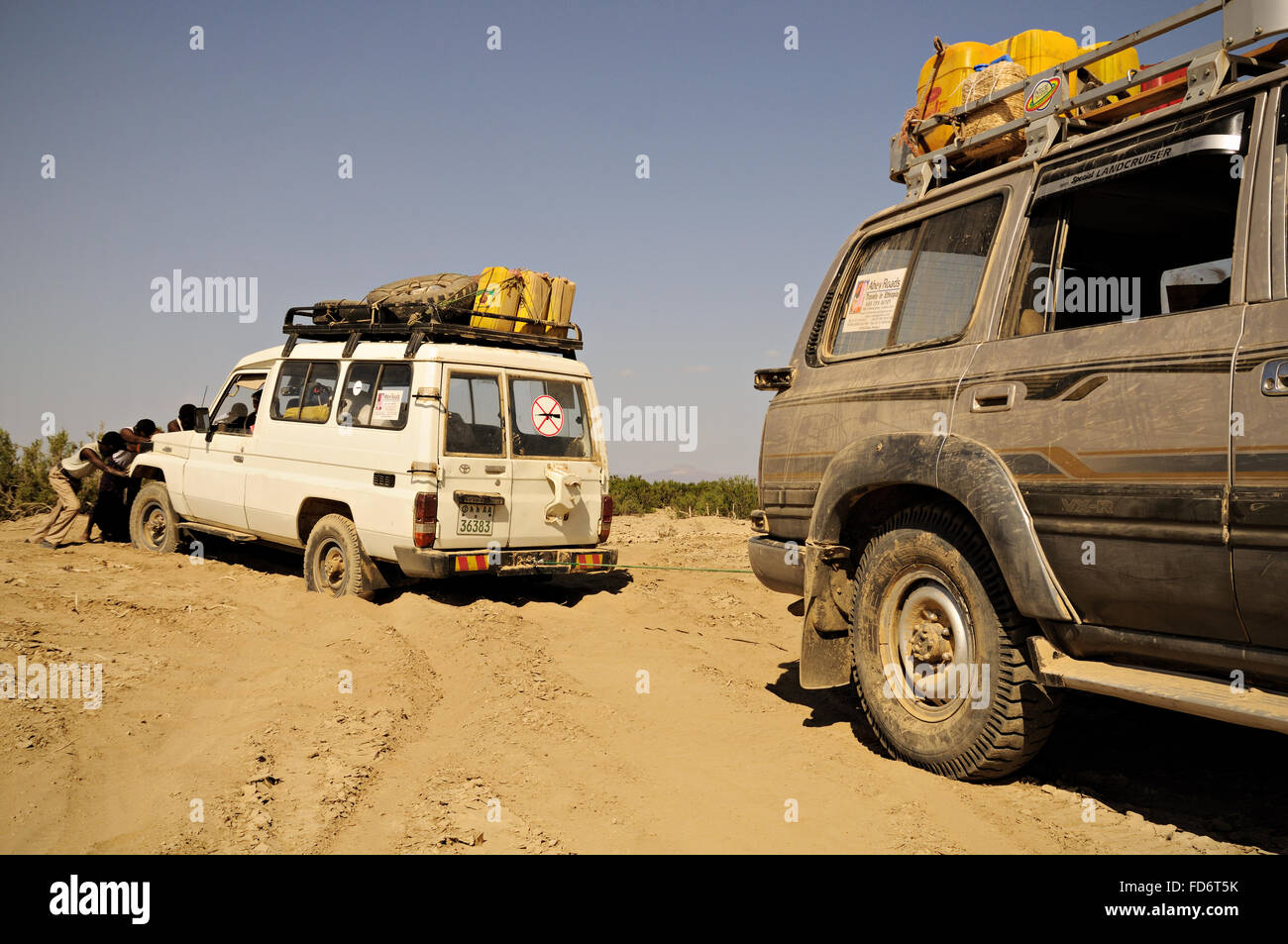 Men pushing a Toyota stuck in the sand in the Danakil depression, Afar Region, Ethiopia Stock Photo