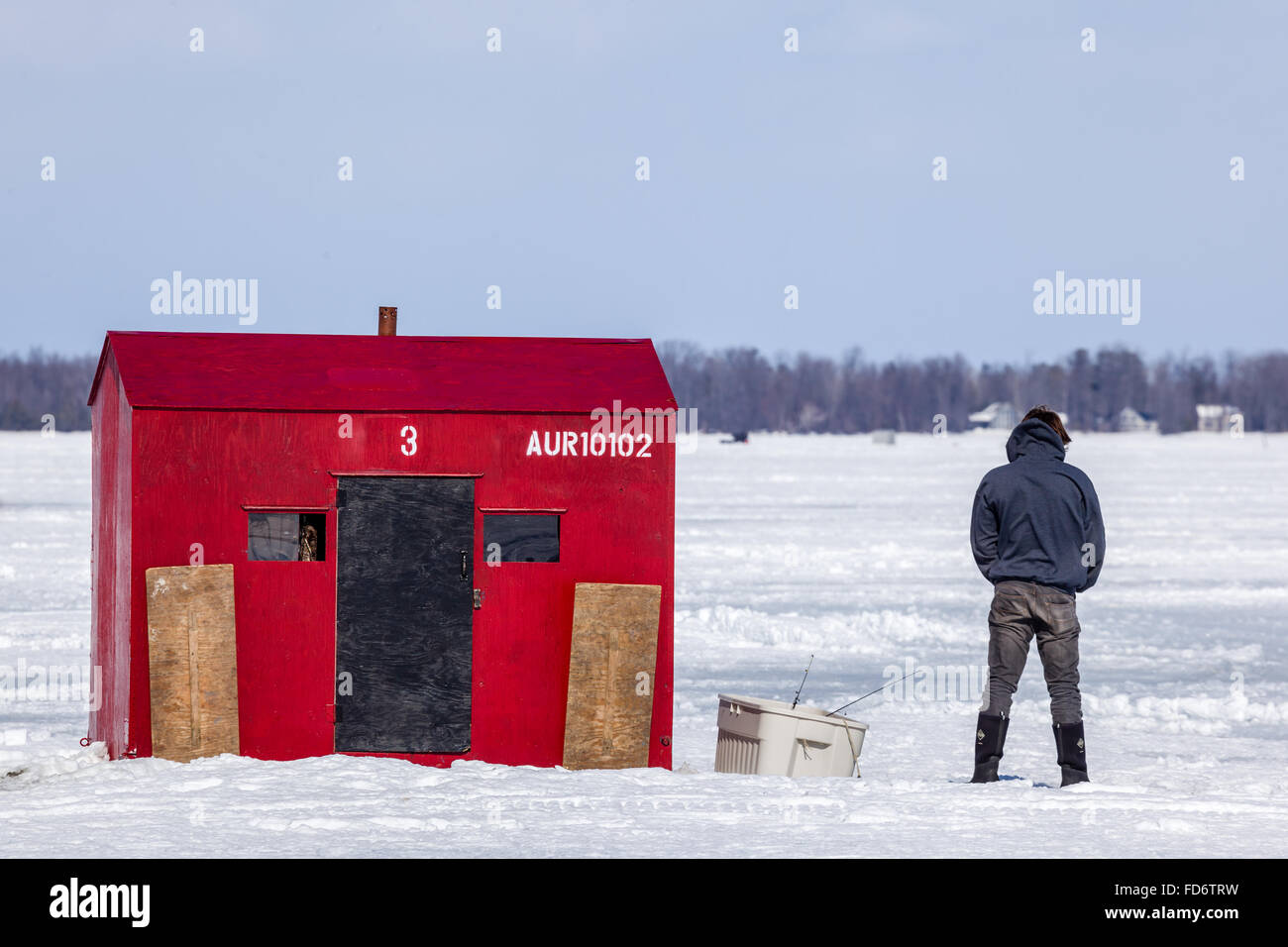 Ice fishing hut on Lake Simcoe with one person with back to camera. Stock Photo