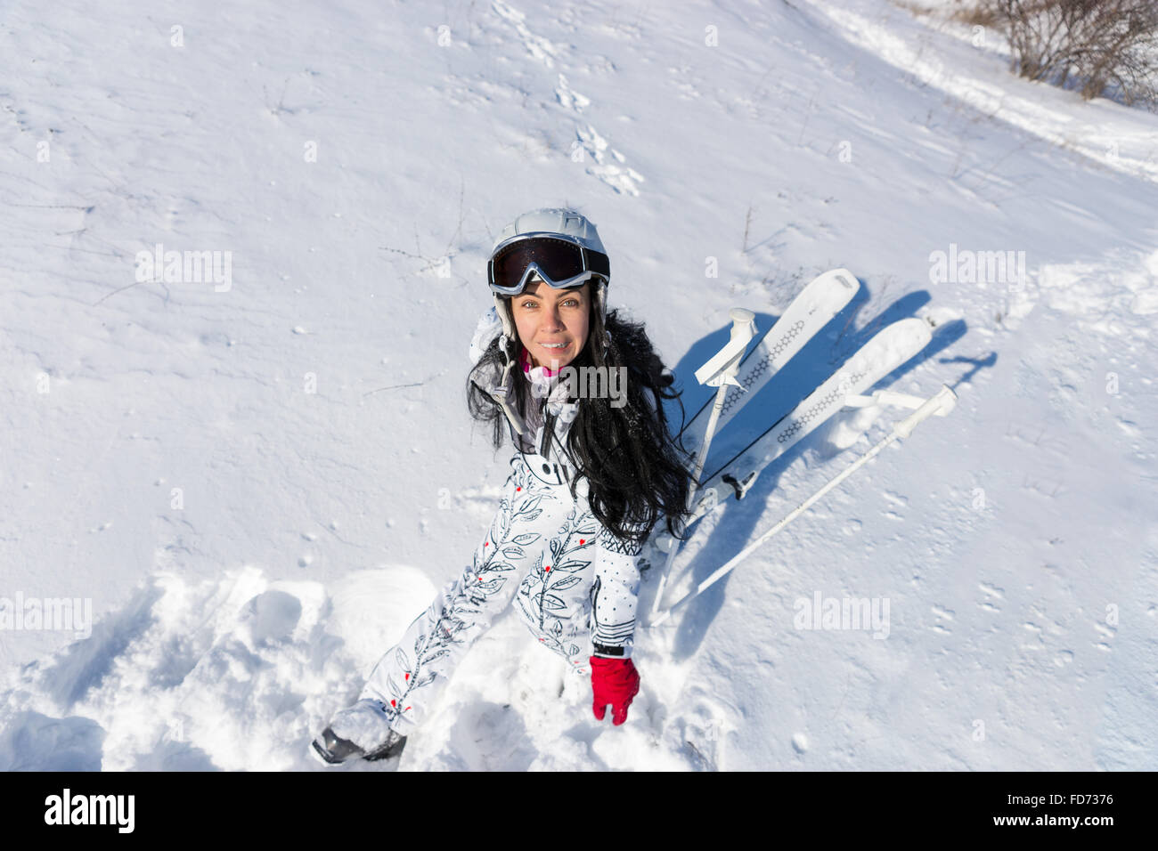 High Angle Full Length View of Young Woman Wearing White Ski Suit and  Helmet Sitting on Snow Covered Mountainside with Skis and Poles on Sunny  Day with Warm Sunshine Stock Photo -