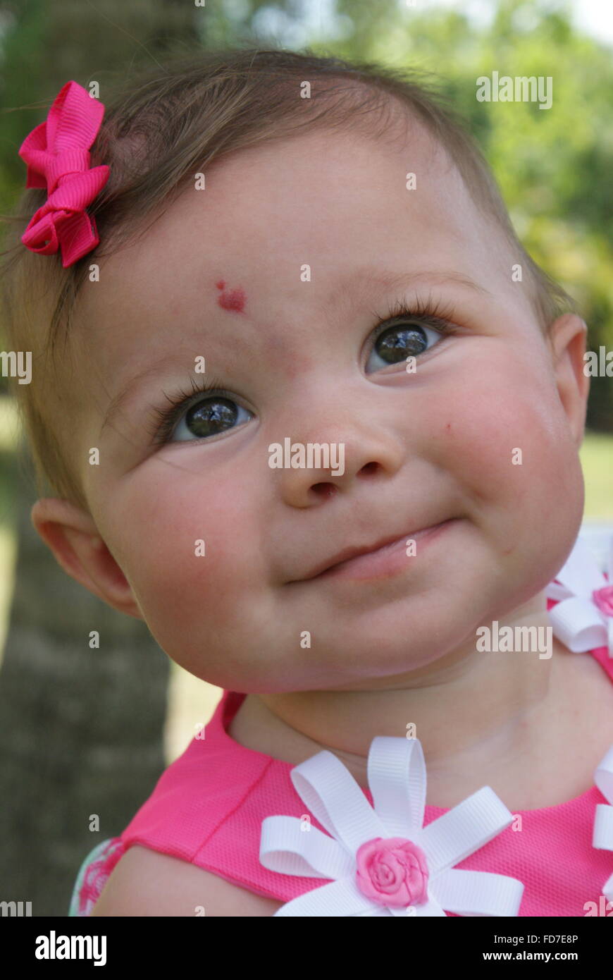 Beautiful little baby girl all dressed up for Easter Sunday. She has a beautiful heart shaped birthmark on her forehead. Stock Photo