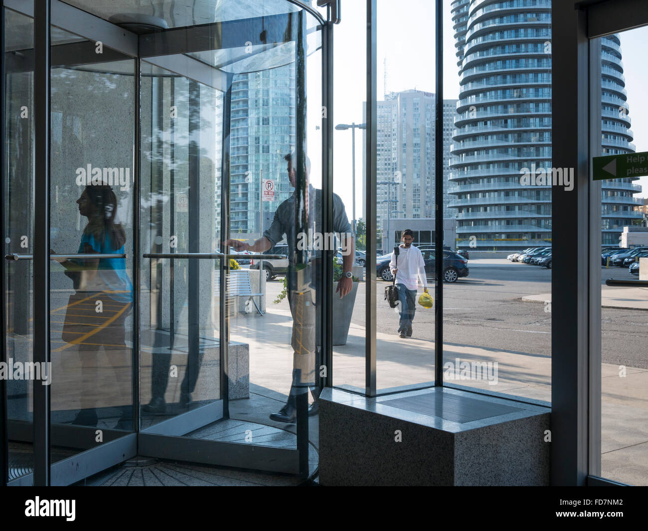 Office workers walking in and out of revolving door at the entrance of an office building. Stock Photo