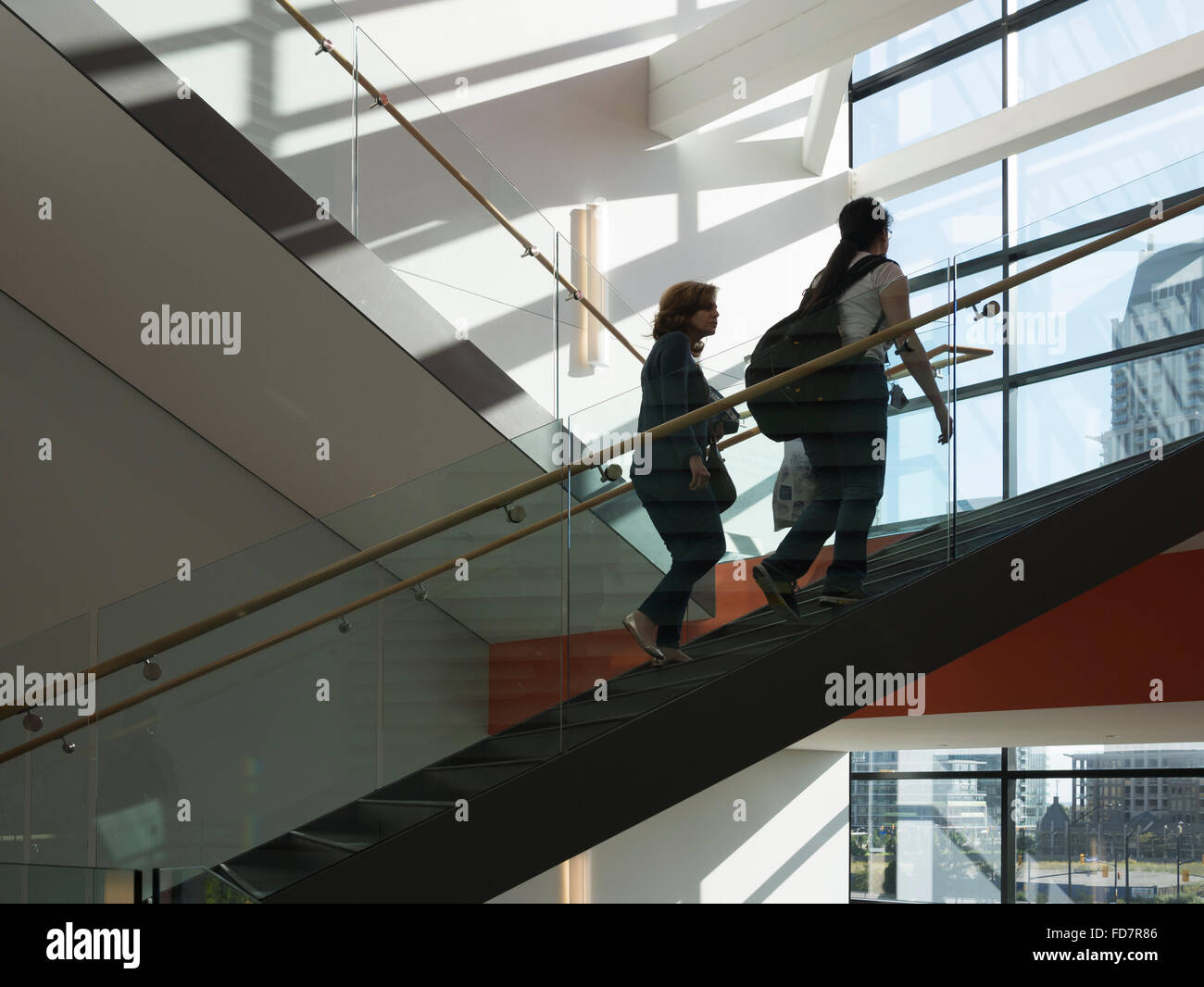 Students walking up and down stairs in a college campus checking smart phone device. Stock Photo