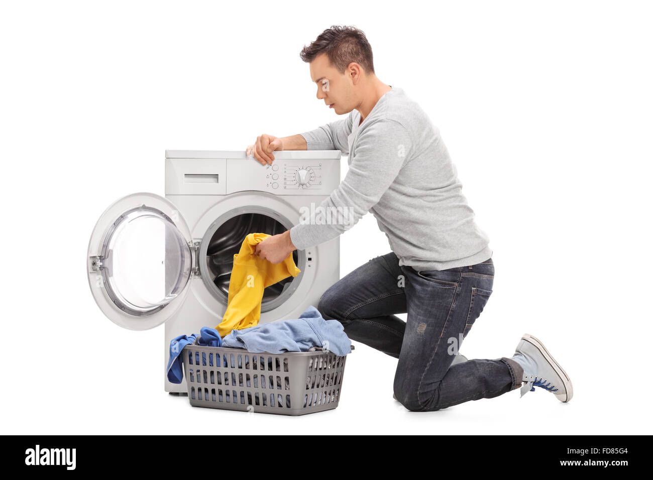 Studio shot of a young man putting clothes in a washing machine isolated on white background Stock Photo