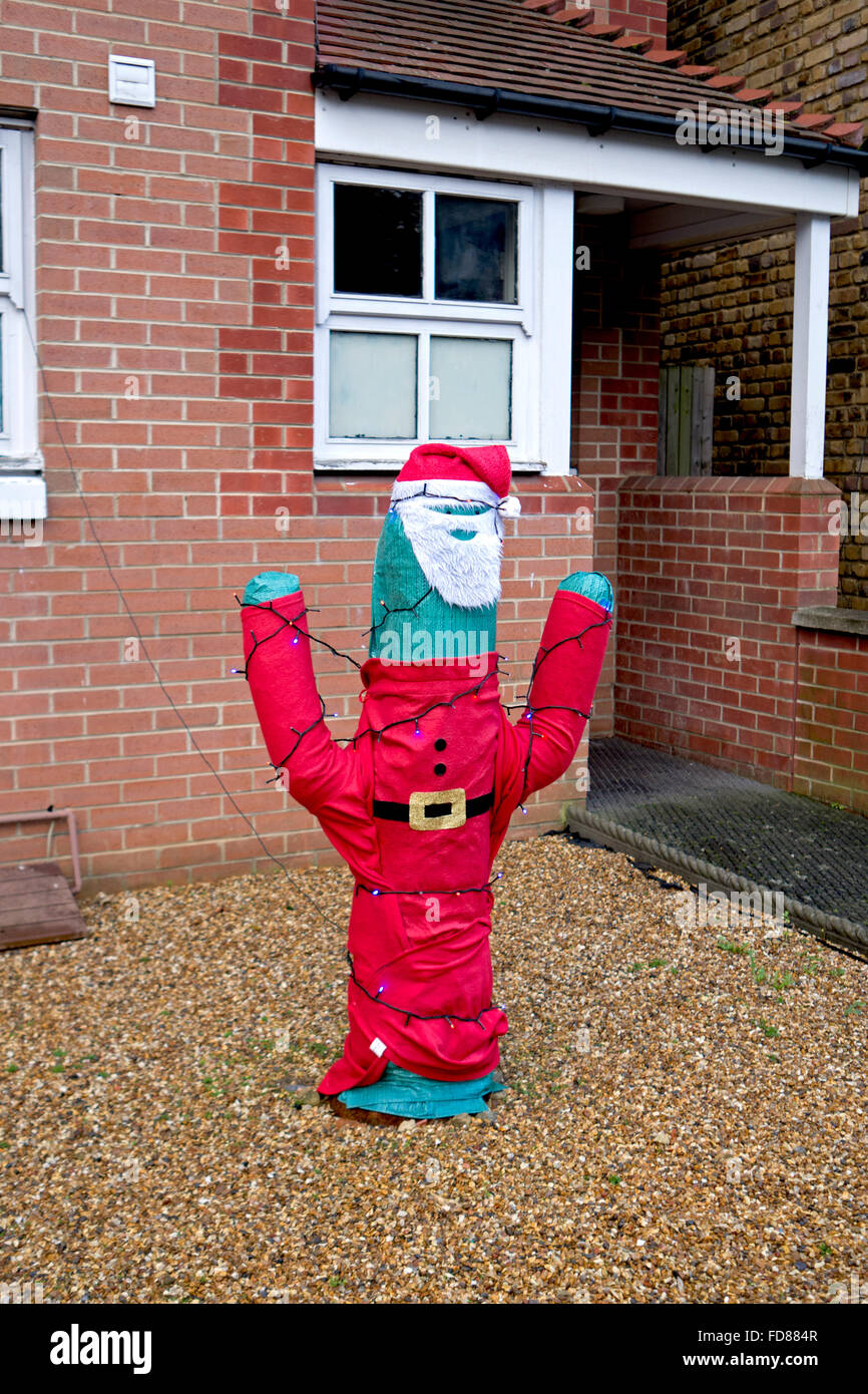 A cactus dressed in a Santa Claus outfit outside a house. Stock Photo