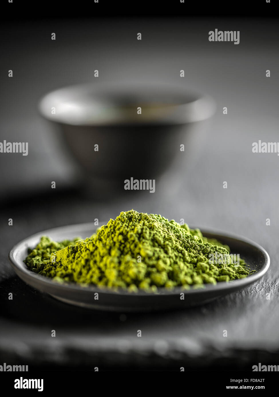 Macha green powder in a plate on black background Stock Photo