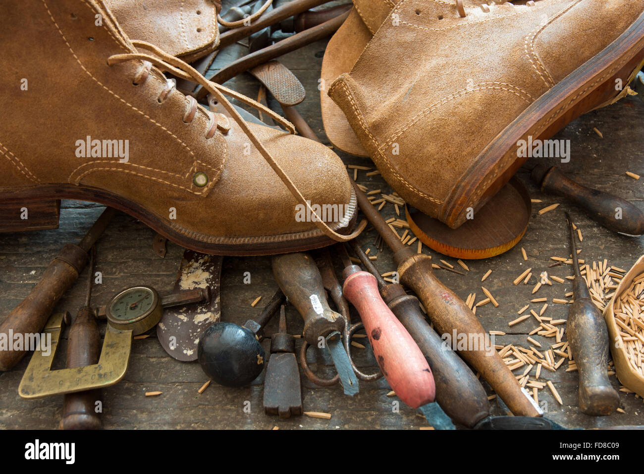 Old shoemaker tools with handmade shoes on bench Stock Photo