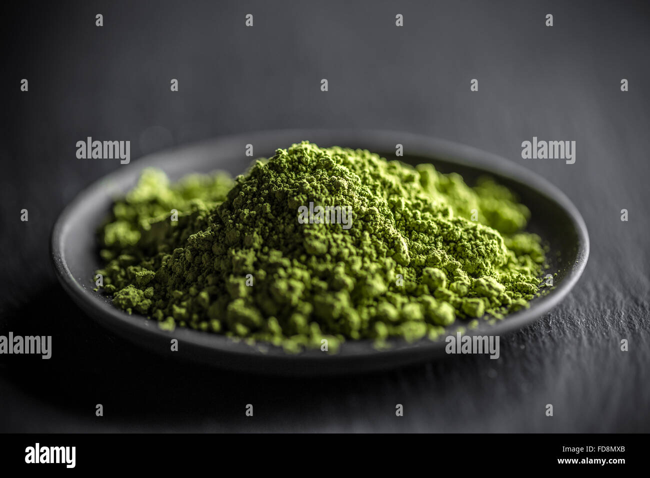 Macha green powder in a plate on black background Stock Photo