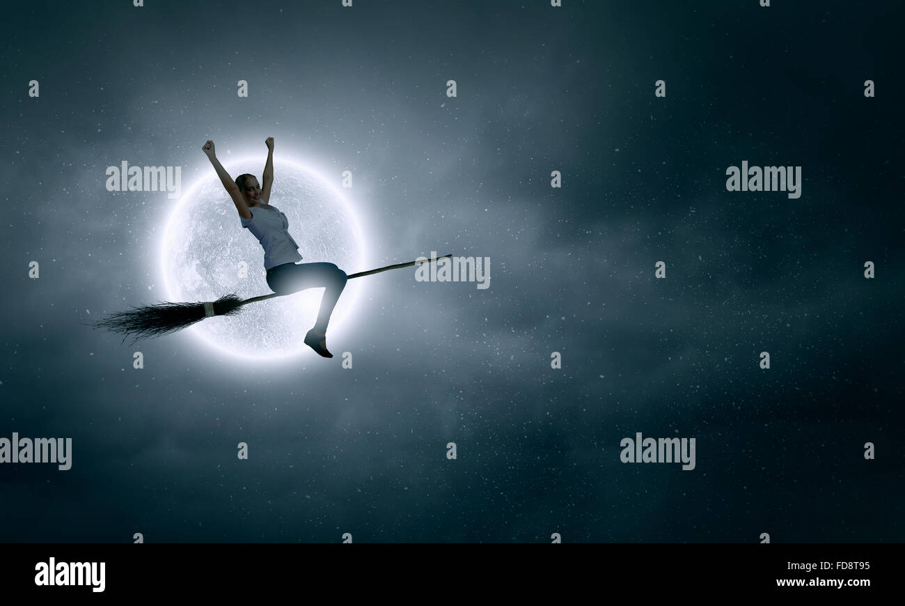 Young girl in casual flying on broom high in sky Stock Photo Alamy