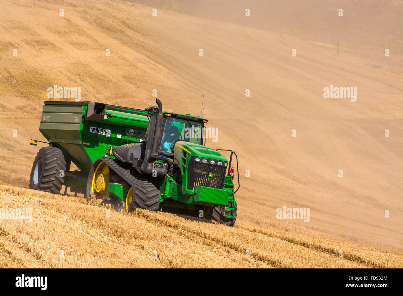 John Deere tractor pulling a grain cart during wheat harvest in the