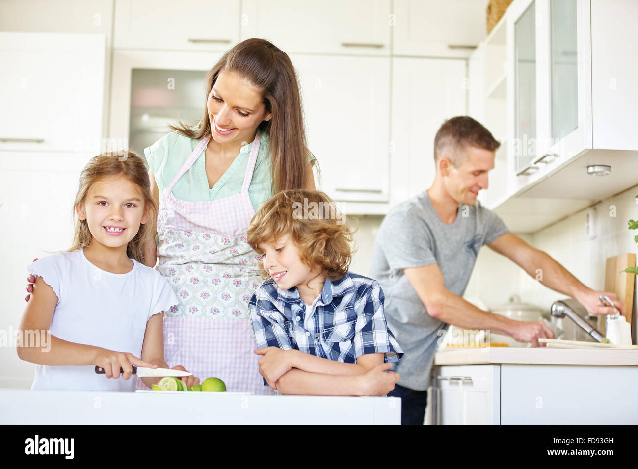 Family with two kids working in kitchen and cutting lime fruits Stock Photo