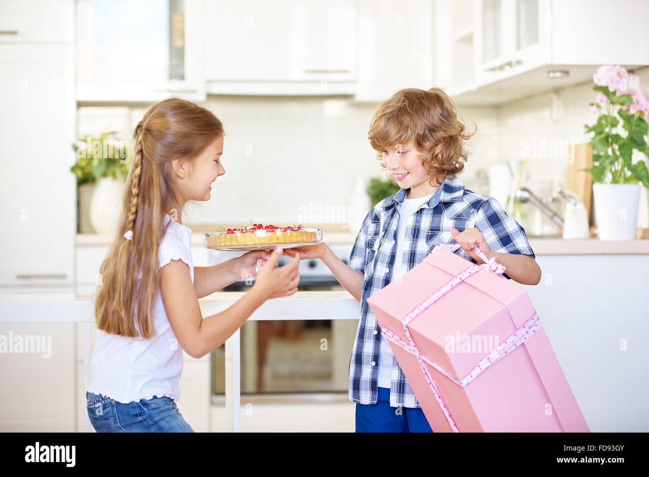 Two children with gift and homemade fruit cake as birthday surprise Stock Photo