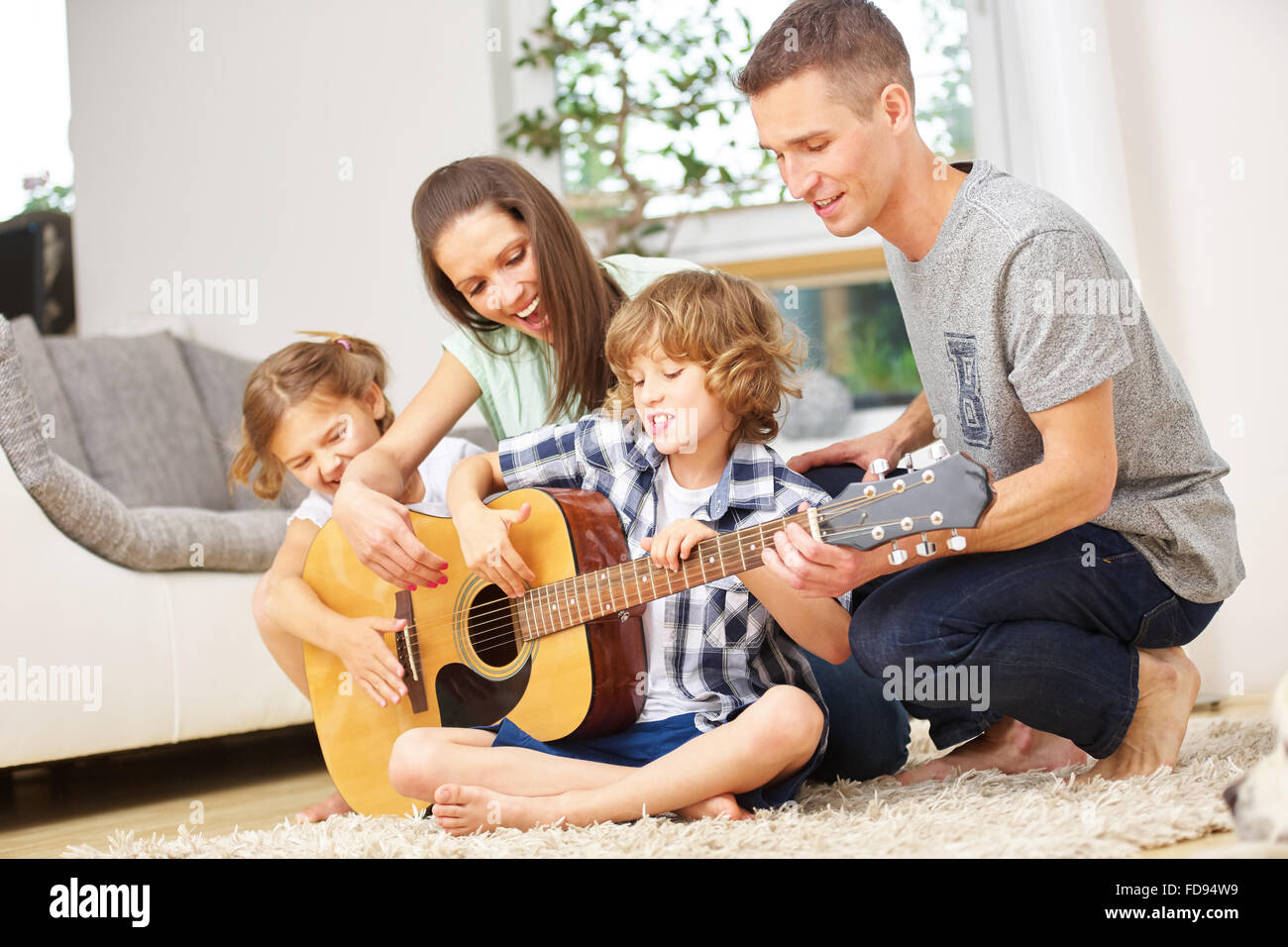 Parents and children playing guitar at home in the living room Stock Photo