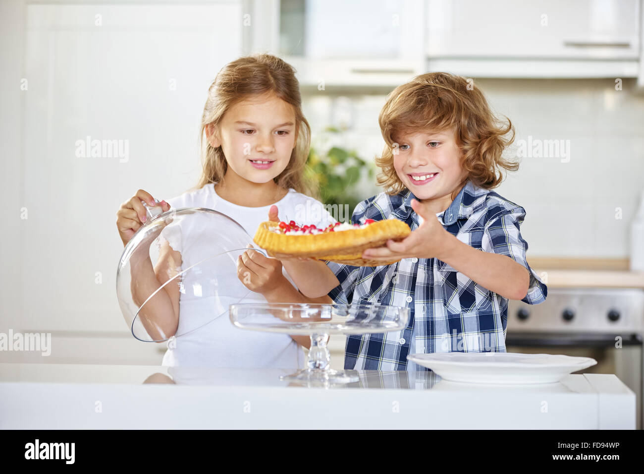 Children presenting their homemade fruitcake in the kitchen Stock Photo