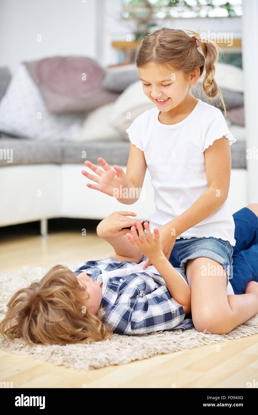 Two siblings fighting in fun at home in the living room Stock Photo