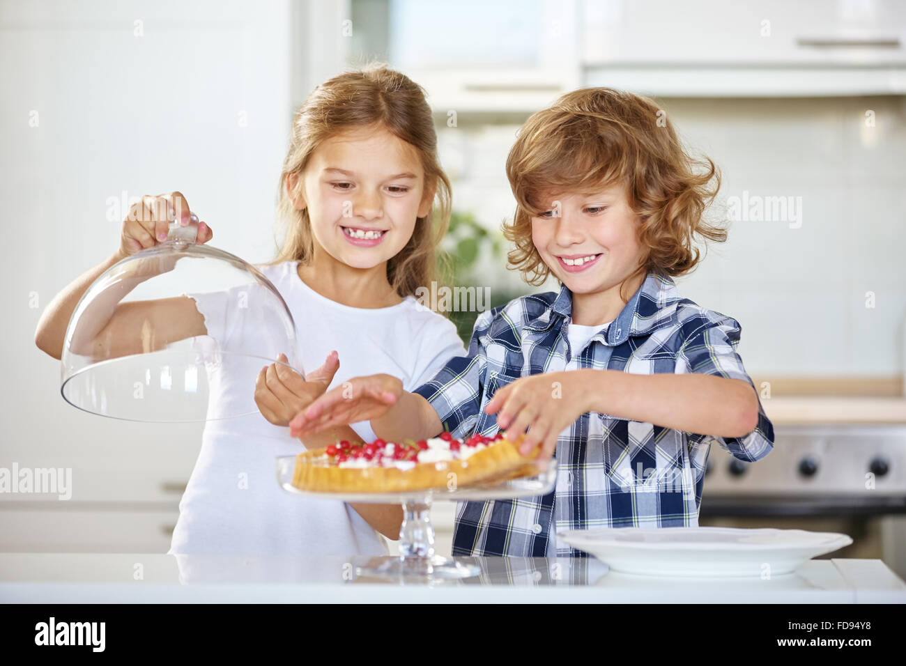 Two proud kids with their first homemade fruitcake in the kitchen Stock Photo