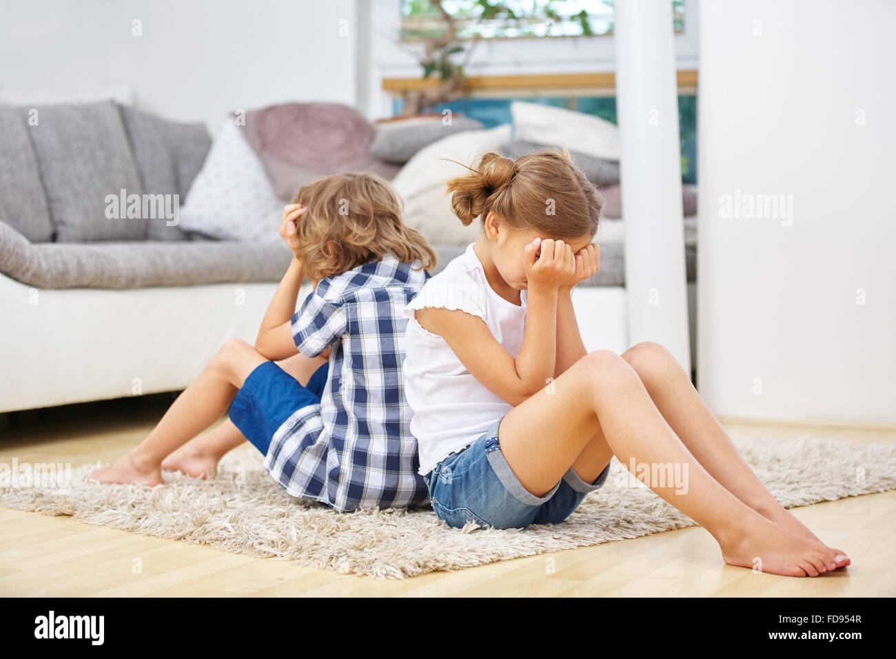 Two siblings pouting in silence after fight at home Stock Photo