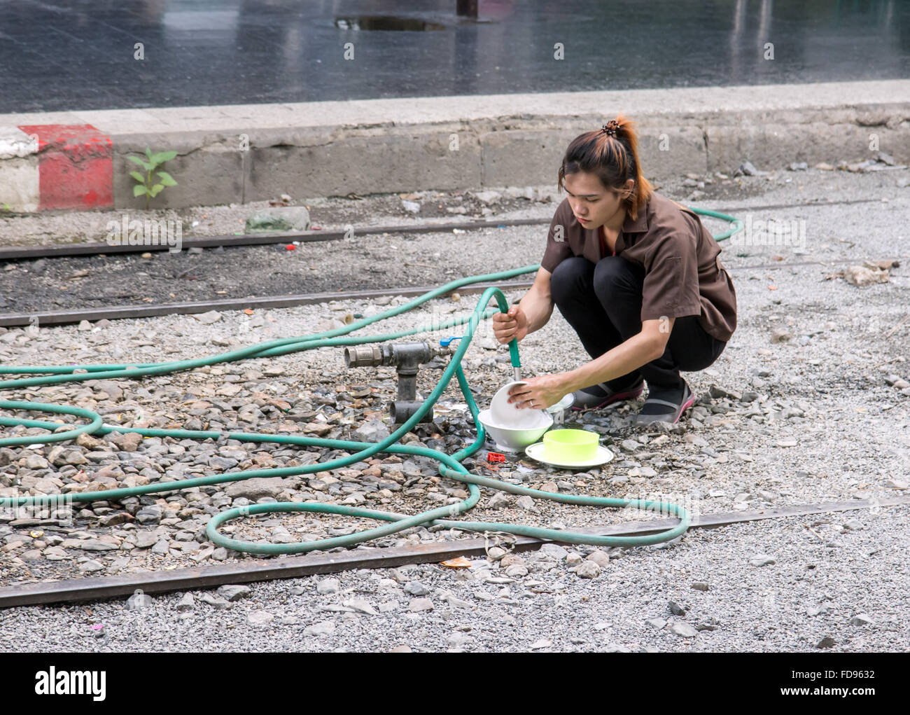 woman washes dishes between the tracks at the station Stock Photo