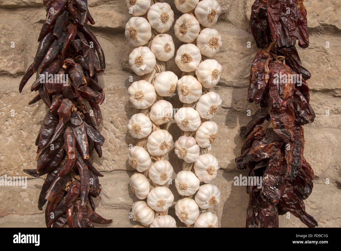 Garlic and Peppers Hanging from a Stone Wall Stock Photo - Alamy