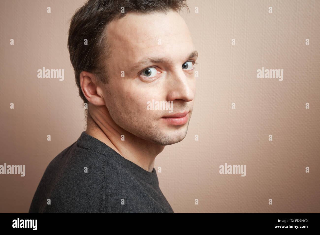 Young positive Caucasian man studio portrait over gray wall background Stock Photo